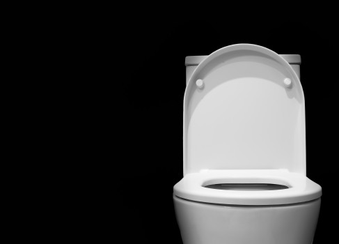 White toilet bowl in a bathroom with black background