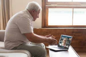 70s father talking with 60s daughter by videocall using laptop