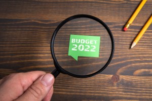 Budget for 2022. Speech bubble and magnifying glass on a wooden background