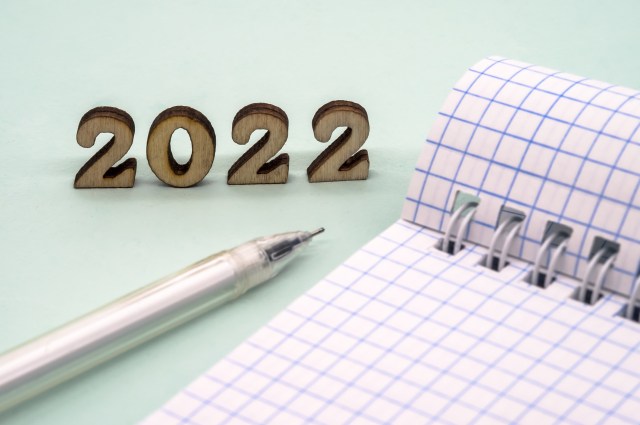 Notebook and pen on the table. A blank sheet of paper and a ballpoint pen. Wooden numbers 2022.