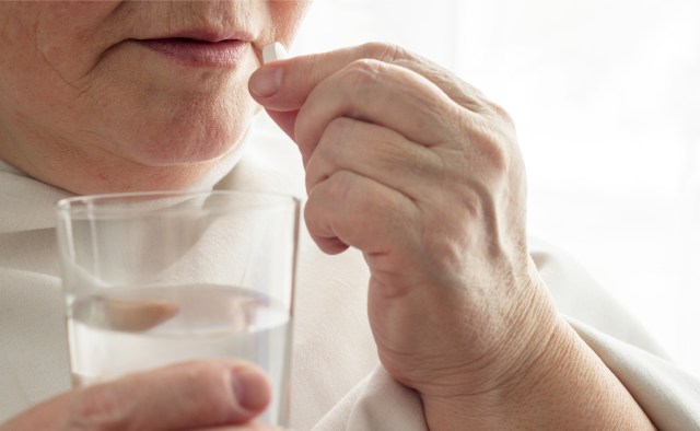 Elderly woman drinks a pill, glass of water, close-up