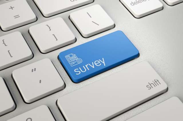 High quality render of a modern computer keyboard detail with blue survey text on it.