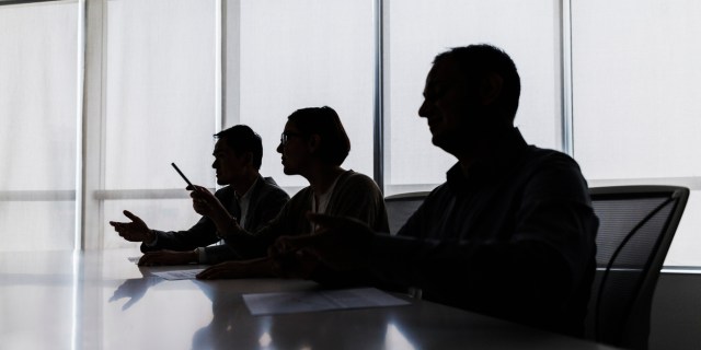 Silhouette of business people negotiating at meeting table wide