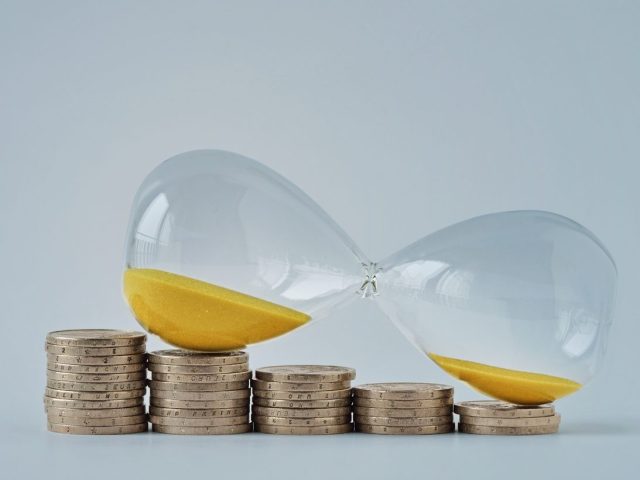 Hourglass on decreasing piles of coins - Concept of money and time