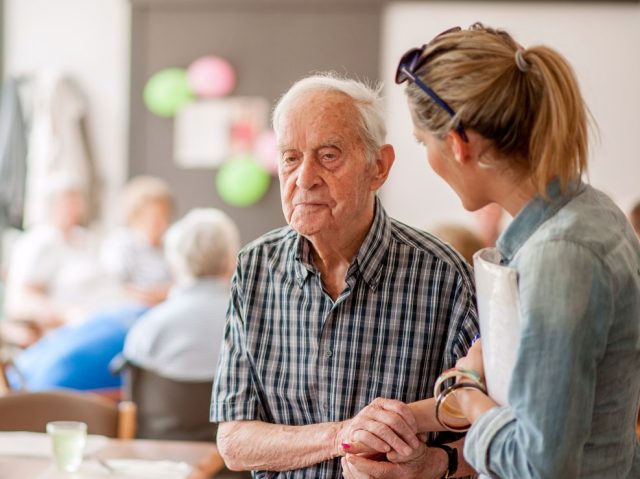 Assistant In The Community Center Giving Advice To A Senior Man