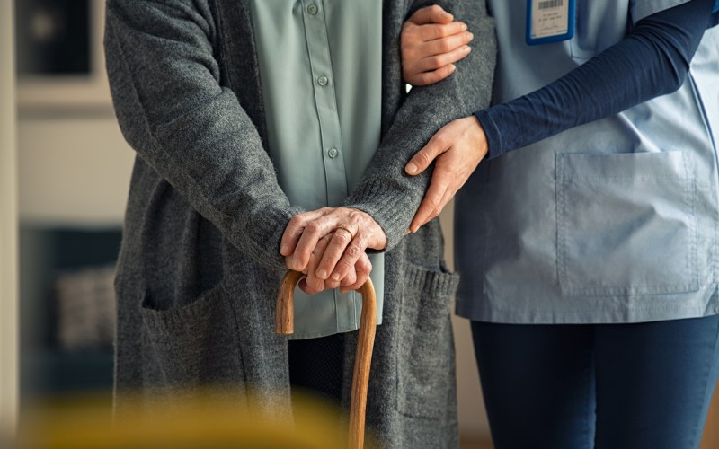 Nurse assisting senior with walking cane
