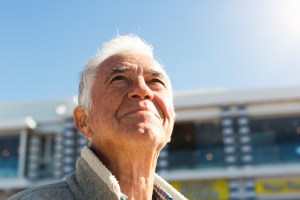 Smiling senior man looks up at sky