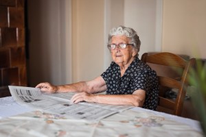 Senior woman with her eyeglasses reading newspapers