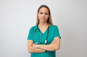 Female nurse standing arms crossed. Confident young woman doctor. Female nurse young pretty woman in green clothes