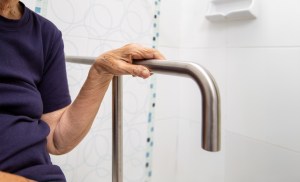 Elderly Woman Gripping Bathroom Safety Rail