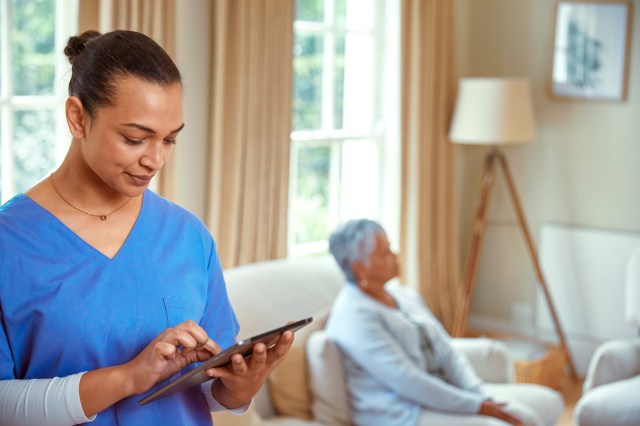 Nurse standing with iPad in patients living room
