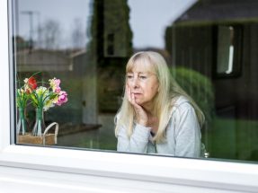 Depressed senior woman looking out of window