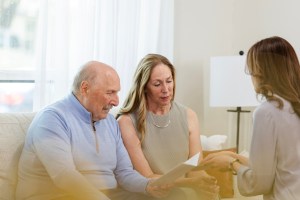 Unrecognizable female social worker helps senior adult couple read over the brochure