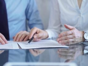 Diverse business people discussing contract papers before signing. Teamwork of lawyers are at work at the glass desk in office