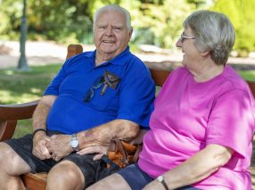 Senior Couple Sitting Talking On a Bench in a Public Park