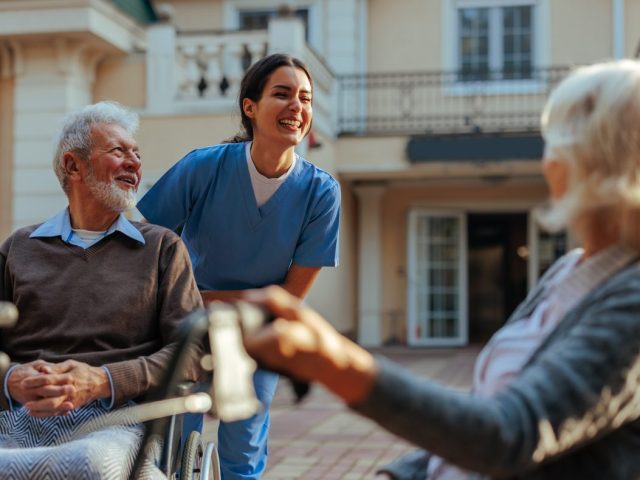 Cheerful caregiver and patients outdoors.