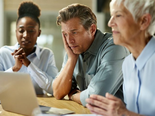 Worried business team working on laptop in the office.