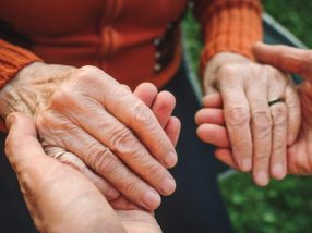 Close-up of a man holding an elderly woman's hands