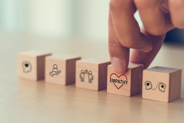 Empathy concept. Wooden blocks with empathy icons on minimal background and copy space. The power of emotional intelligent, soft skill development. Empathy in the workplace, good leaders, good teams.