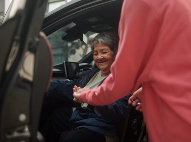 Helping a senior woman out of the car.