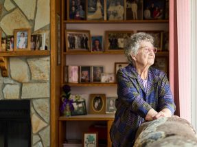 Senior woman looking out through her living room window